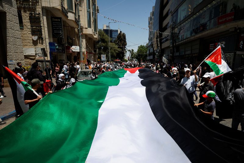 &copy; Reuters. فلسطينيون يرفعون الأعلام الوطنية خلال مسيرات في رام الله بالضفة الغربية يوم الاثنين في الذكرى الخامسة والسبعين للنكبة . تصوير : محمد تركمان 