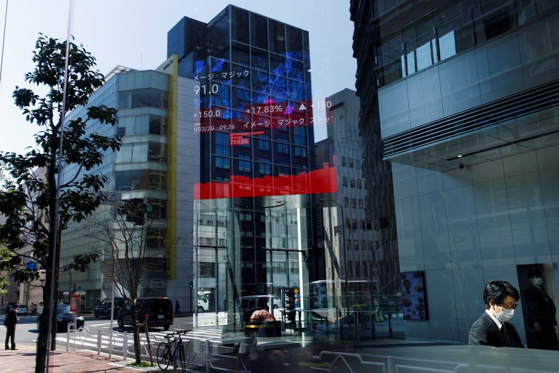 &copy; Reuters. FILE PHOTO: A man uses a laptop, under an electronic board showing stock visualizations, inside a brokerage building, in Tokyo, Japan, March 20, 2023. REUTERS/Androniki Christodoulou