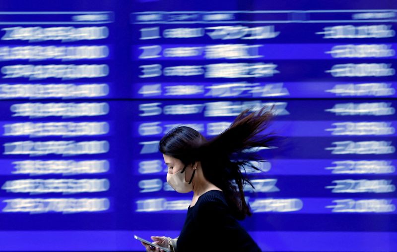 &copy; Reuters. FILE PHOTO: A passerby walks past an electric monitor displaying recent movements of various stock prices outside a bank in Tokyo, Japan, March 22, 2023. REUTERS/Issei Kato    
