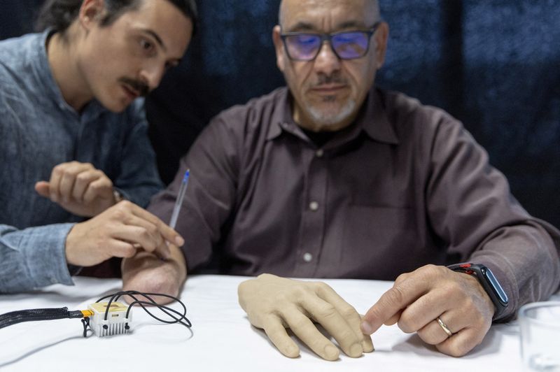 &copy; Reuters. Fabrizio Fidati, who lost his right hand in an accident 25 years ago, points on a rubber hand where he feels on his fantom hand the pen that Francesco Iberite, neural engineer at the Scuola Superiore Sant'Anna (SSSA), applies on his limb  during the prese