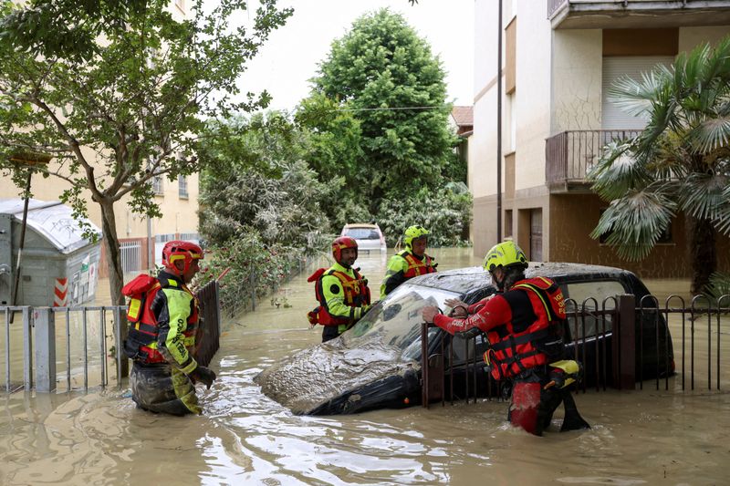 &copy; Reuters. رجال الإطفاء يعملون بجانب سيارة غمرتها مياه الفيضانات يوم الخميس في أعقاب أمطار غزيرة وسيول اجتاحت منطقة إيميليا-رومانيا بشمال إيطاليا. تص