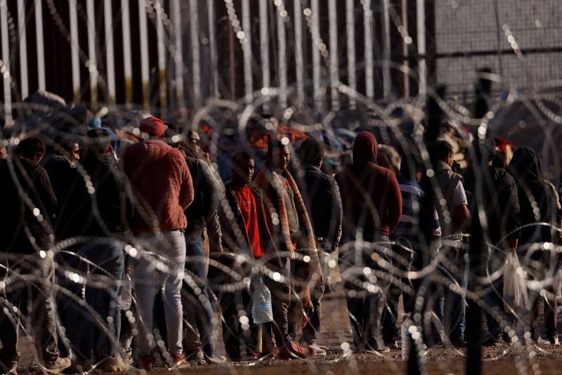 &copy; Reuters. FILE PHOTO: Migrants stand near the border wall after having crossed the U.S.-Mexico border to turn themselves in to U.S. Border Patrol agents, after the lifting of COVID-19 era Title 42 restrictions that have blocked migrants at the border from seeking a