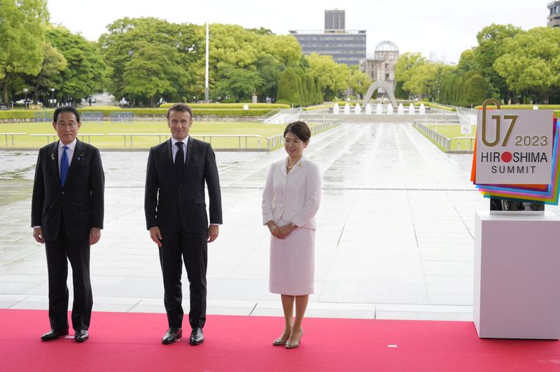 © Reuters. French President Emmanuel Macron poses for a photo with Japan’s Prime Minister Fumio Kishida and his wife Yuko Kishida at the Peace Memorial Park during a visit as part of the G7 Hiroshima Summit in Hiroshima, Japan, 19  May 2023. The G7 Hiroshima Summit will be held from 19 to 21 May 2023.    FRANCK ROBICHON/Pool via REUTERS