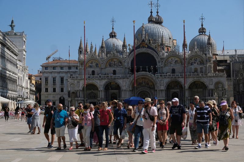 © Reuters. FILE PHOTO: Tourists walk in St. Mark's Square as the municipality prepares to charge them up to 10 Euro for entry into the lagoon city, in order to cut down the number of visitors, in Venice, Italy, September 5, 2021. Picture taken September 5, 2021. REUTERS/Manuel Silvestri/File Photo