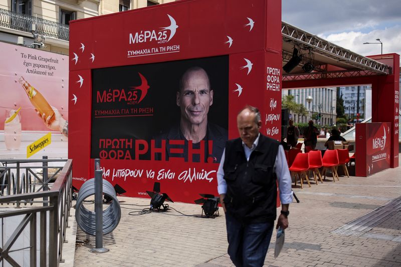© Reuters. A man walks past the pre-election kiosk of the MeRA25 party, depicting the party's leader Yanis Varoufakis, in Athens, Greece, May 18, 2023. REUTERS/Stelios Misinas