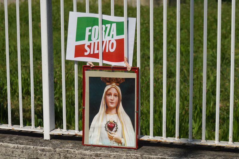 &copy; Reuters. FOTO DE ARCHIVO-Una imagen que representa a la Virgen María junto a un logotipo del partido Forza Italia fuera del hospital 'San Raffaele' donde el ex primer ministro italiano Silvio Berlusconi está hospitalizado, en Milán, Italia. 3 de mayo de 2023. R