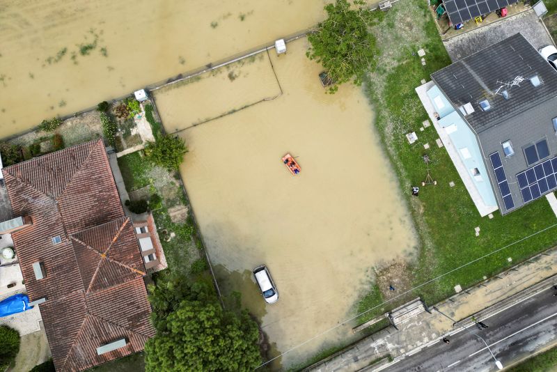 © Reuters. Residents use a boat to navigate through flood water after heavy rains hit Italy's Emilia Romagna region, in San Pancrazio near Ravenna, Italy, May 18, 2023. REUTERS/Antonio Denti