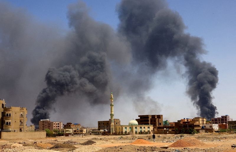 © Reuters. FILE PHOTO: A man walks while smoke rises above buildings after aerial bombardment, during clashes between the paramilitary Rapid Support Forces and the army in Khartoum North, Sudan, May 1, 2023. REUTERS/Mohamed Nureldin Abdallah/File Photo