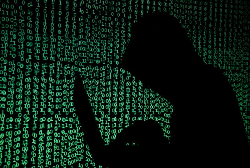 &copy; Reuters. FILE PHOTO: A hooded man holds a laptop computer as cyber code is projected on him in this illustration picture taken on May 13, 2017.  REUTERS/Kacper Pempel/Illustration