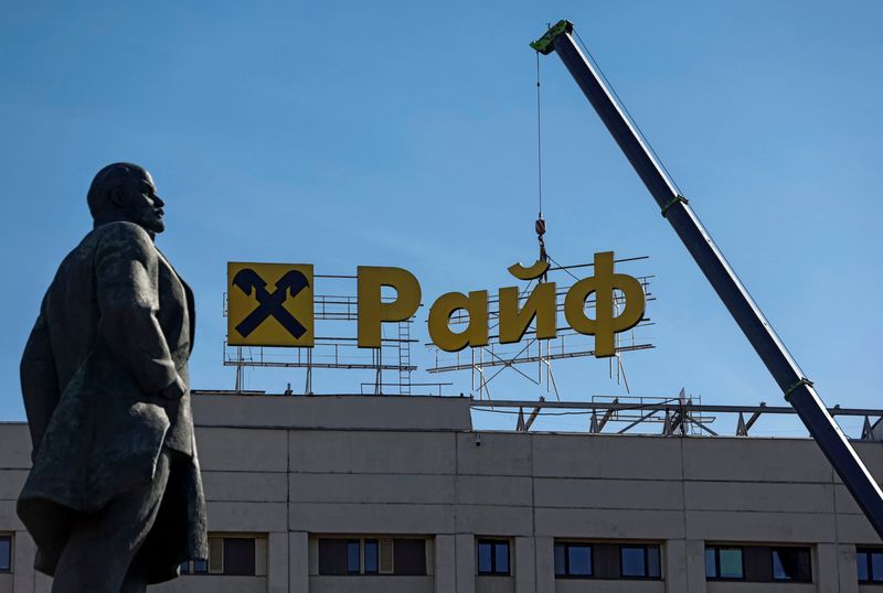 © Reuters. FILE PHOTO: Workers use a crane to dismantle a signboard advertising Raiffeisen Bank from a building, as a monument to Soviet state founder Vladimir Lenin is seen in the foreground, in Moscow, Russia April 14, 2023. REUTERS/Maxim Shemetov