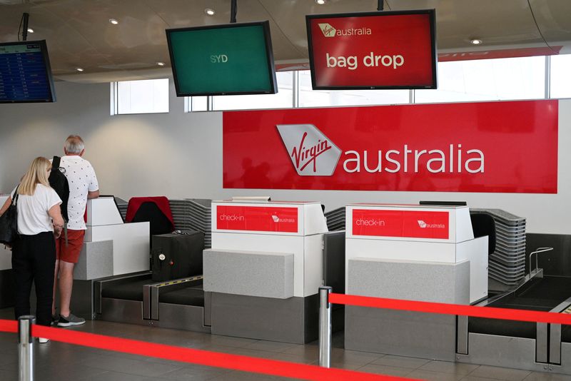 &copy; Reuters. FILE PHOTO: Travelers stand at a Virgin Australia Airlines counter at Kingsford Smith International Airport, following the coronavirus outbreak, in Sydney, Australia, March 18, 2020.  REUTERS/Loren Elliott