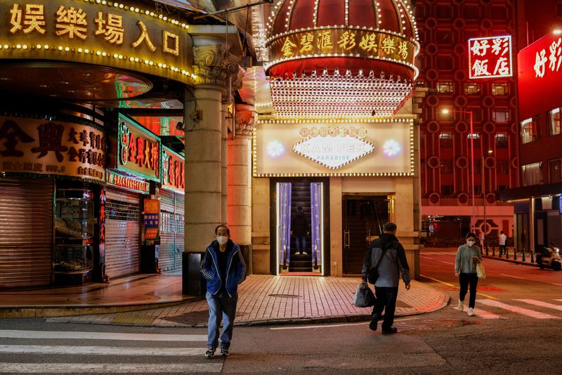 &copy; Reuters. FILE PHOTO: People wearing face masks walk under neon lights near casinos during the coronavirus disease (COVID-19) pandemic in Macau, China, December 29, 2022. REUTERS/Tyrone Siu