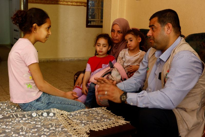 © Reuters. الفتاة الفلسطينية بيسان المنسي تتحدث مع طبيب نفسي في منزلها بدير البلح في وسط قطاع غزة يوم 16 مايو أيار 2023. تصوير: إبراهيم أبو مصطفي - رويترز.
