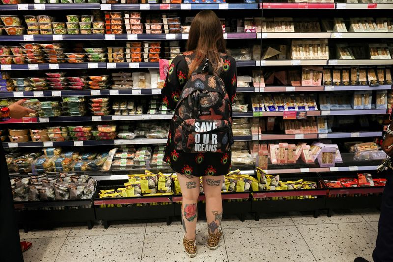 © Reuters. FILE PHOTO: A person wearing a backpack looks at food goods in a shop as UK inflation heads towards 10% in London, Britain, June 16, 2022.   REUTERS/Kevin Coombs