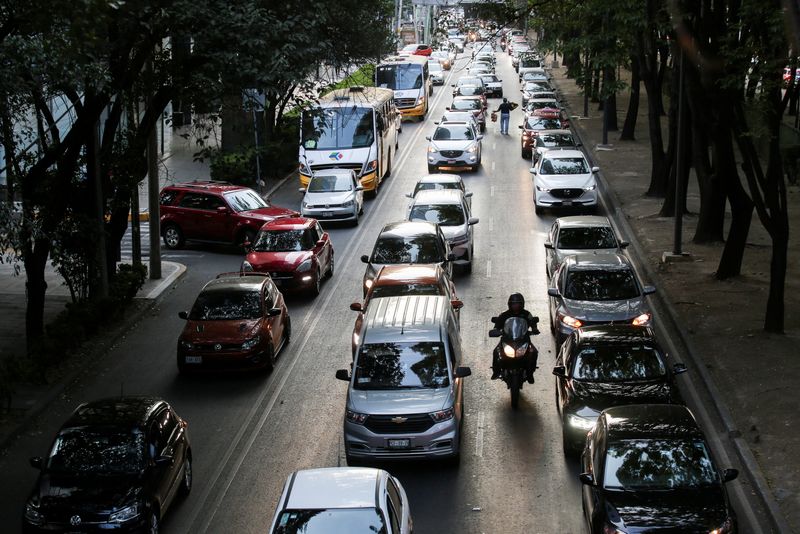 © Reuters. FILE PHOTO: A man rides his motorcycle past cars queue in traffic during rush hour in Mexico City, Mexico, March 3, 2023. REUTERS/Quetzalli Nicte-Ha