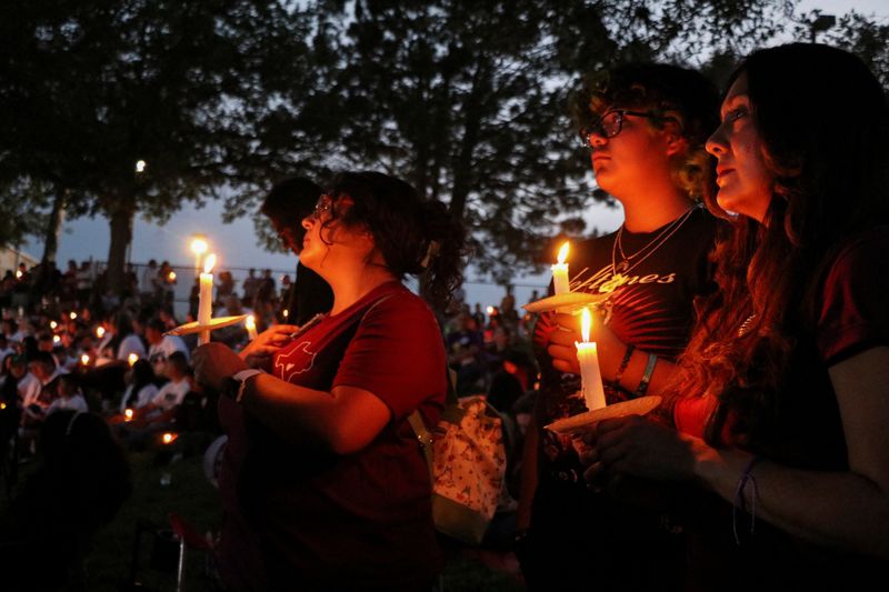 © Reuters. Attendees hold candles during a vigil at Uvalde Memorial Park, one year after a gunman killed 19 children and two adults in Robb Elementary School, in Uvalde, Texas, May 24, 2023. REUTERS/ Evan Garcia