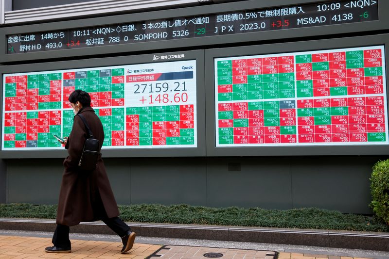 &copy; Reuters. FILE PHOTO: A man walks past an electronic board showing Japan's Nikkei average and stock prices outside a brokerage, in Tokyo, Japan, March 17, 2023. REUTERS/Androniki Christodoulou