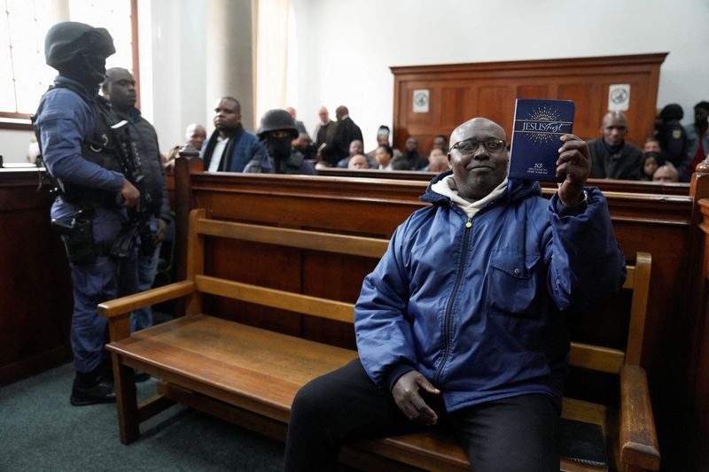 © Reuters. Rwandan genocide suspect Fulgence Kayishema holds up a Christian book, as he appears in the Cape Town Magistrates Court, in Cape Town, South Africa May 26, 2023. REUTERS/Nic Bothma     