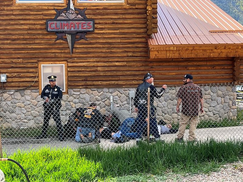 &copy; Reuters. A police officer stands guard as man with a Bandidos MC patch assists a shot biker in Red River, New Mexico after a shootout between members of two motorcycle gangs at an annual Memorial Day motorbike rally, in this handout picture taken on May 27, 2023. 
