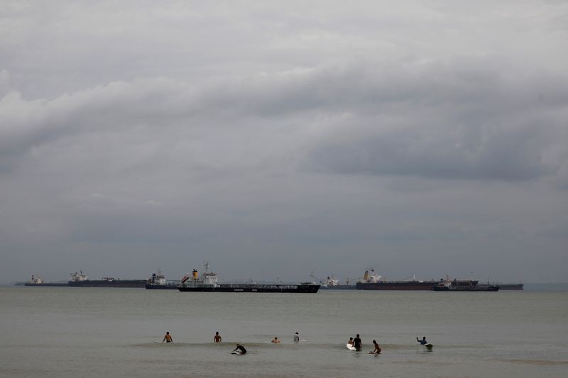 &copy; Reuters. FILE PHOTO: Surfers wait to catch a wave along a beach surrounded by tankers in Singapore January 14, 2021. REUTERS/Edgar Su