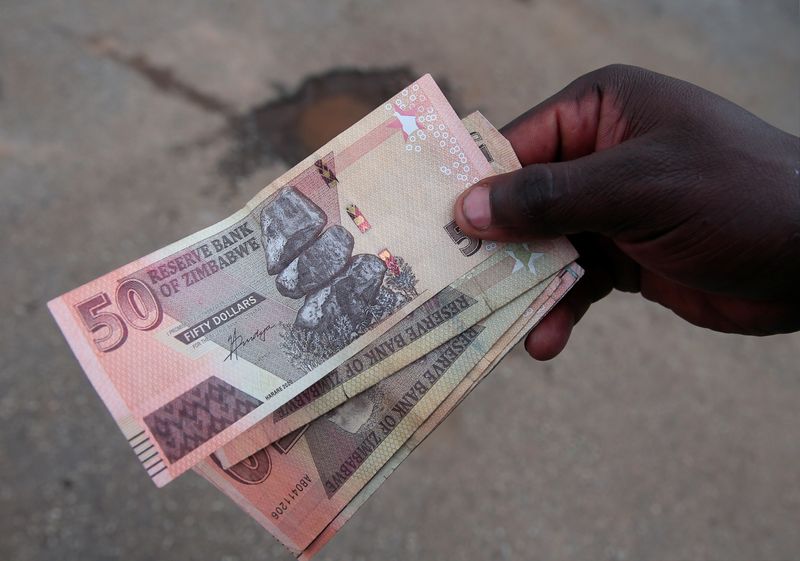 &copy; Reuters. FILE PHOTO: A man shows off Zimbabwean currency notes outside a grocery store in Harare, Zimbabwe, March 17, 2022. Picture taken March 17, 2022. REUTERS/Philimon Bulawayo
