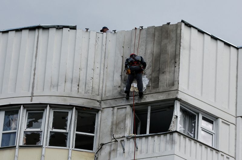 &copy; Reuters. عاملان يصلحان الضرر اللاحق بمنبى سكني جراء هجوم بطائرات مسيرة في موسكو يوم الثلاثاء. تصوير: ماكسيم شيمتوف - رويترز.