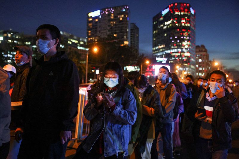 &copy; Reuters. FILE PHOTO: People line up at a bus stop during evening rush hour in Beijing as outbreaks of coronavirus disease (COVID-19) continue, in China, October 19, 2021. REUTERS/Thomas Peter/File Photo