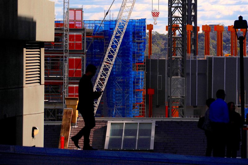 © Reuters. FILE PHOTO: Pedestrians walk in front of a crane and scaffolding on a construction site in central Sydney, Australia, May 31, 2018.   REUTERS/David Gray