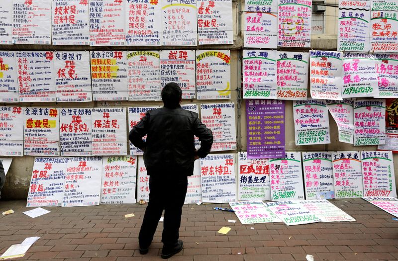 &copy; Reuters. FILE PHOTO: A man looks at job information at an employment fair beside a street in Zhengzhou, Henan province, February 19, 2014. REUTERS/Jason Lee