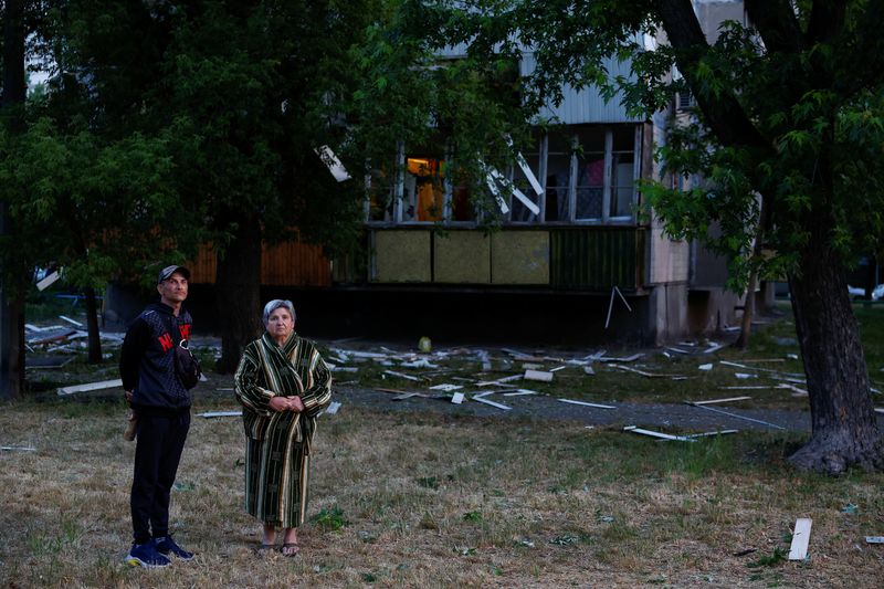 © Reuters. إثنان من السكان المحليين يقفان بجوار مبنى سكني تعرض لأضرار جراء قصف بالصورايخ الروسية على العاصمة الأوكرانية كييف يوم الخميس . تصوير : فالنتين أوجيرينكو - رويترز .   