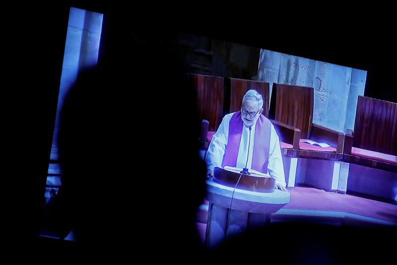 &copy; Reuters. Photo d'archives: Un journaliste regarde un flux télévisé en direct alors que le prêtre Josu Lopez Villalba, victime d'abus sexuels, parle lors d'une messe, qu'il tient aux côtés de l'évêque de Bilbao, Joseba Segura, où le pardon a été demandé