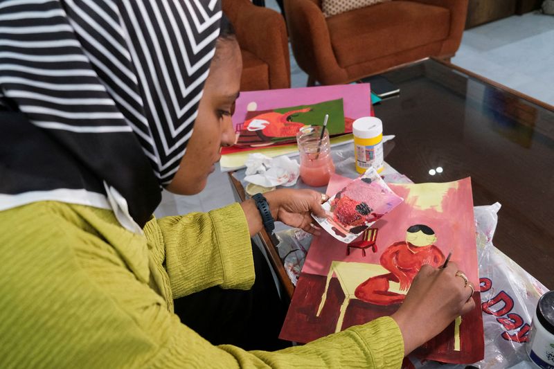 &copy; Reuters. FILE PHOTO: Reem Al Jeally, a Sudanese artist, works on a new painting at her rented house in Cairo, Egypt May 25, 2023.  Reem, who with other Sudanese artists fled a raging war back home to Egypt, has left behind more than 50 large canvases at her apartm