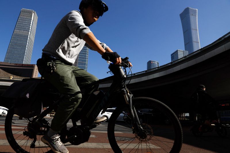&copy; Reuters. FILE PHOTO: A man rides a bicycle past a street at the Beijing's Central Business District (CBD) during morning rush hour, in Beijing, China April 18, 2023. REUTERS/Tingshu Wang