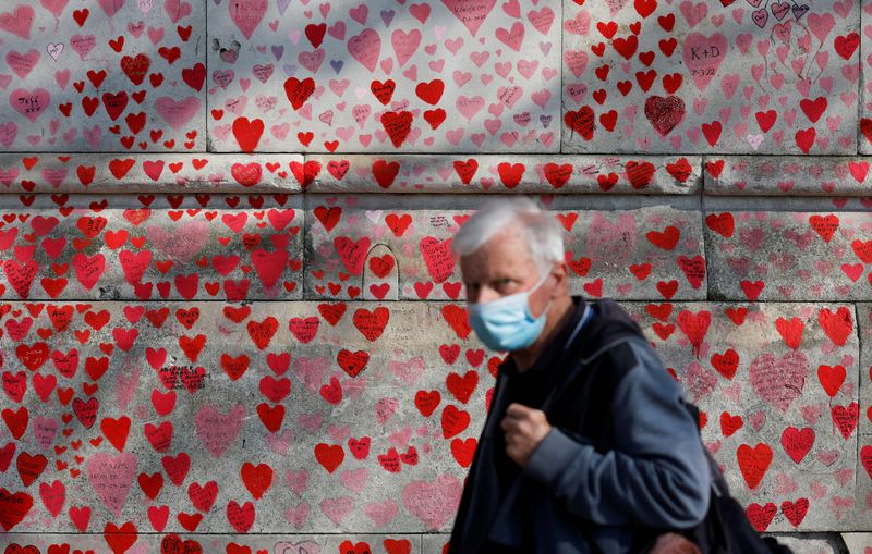 &copy; Reuters. FILE PHOTO: A man wearing a face mask walks past The National Covid Memorial Wall, on national day of reflection to mark the two year anniversary of the United Kingdom going into national lockdown, in London, Britain, March 23, 2022. REUTERS/Peter Cziborr