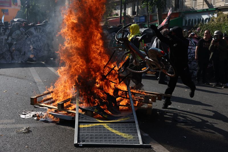 © Reuters. A protester throws a Velib bike at burning fences and wooden pallets during a demonstration as part of the 14th day of nationwide protests against French government's pension reform law, in Paris, France, June 6, 2023. REUTERS/Stephanie Lecocq