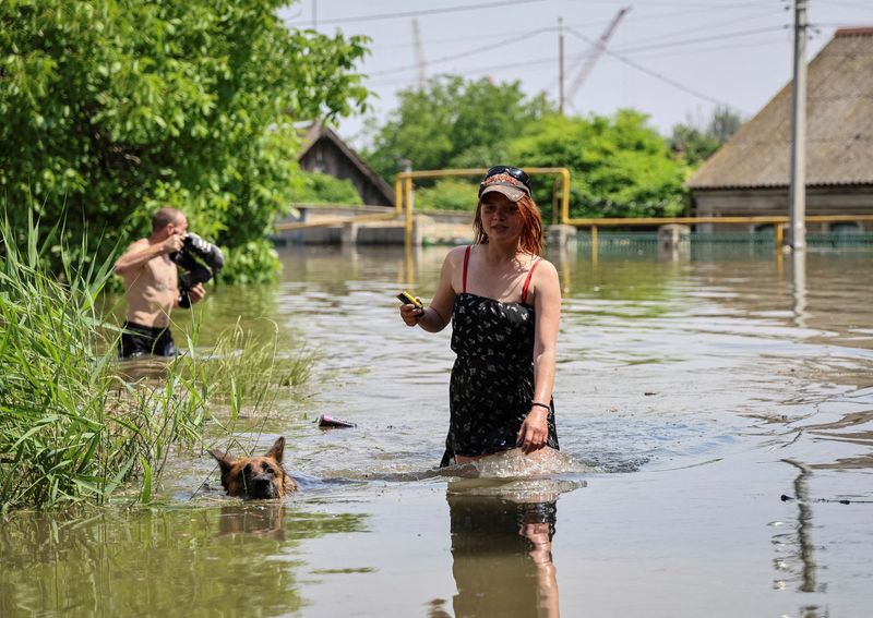 &copy; Reuters. Moradores caminham em uma rua inundada após rompimento da barragem de Nova Kakhovka, em Kherson
07/06/2023
REUTERS/Ivan Antypenko