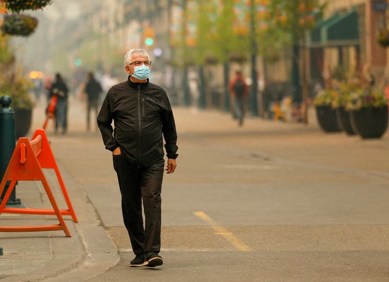 © Reuters. FILE PHOTO: A man wears a mask as some 90 wildfires are active in Alberta, with 23 out of control, according to the provincial government, in Calgary, Alberta, Canada May 16, 2023.  REUTERS/Leah Hennel/File Photo