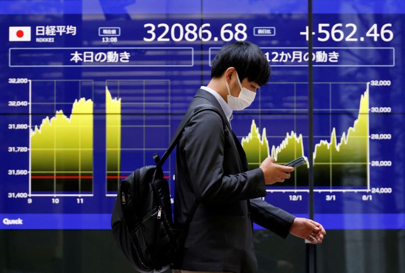 &copy; Reuters. FILE PHOTO: A man walks past an electric monitor displaying Japan's Nikkei share average and recent movements, outside a bank in Tokyo, Japan, June 5, 2023. REUTERS/Issei Kato