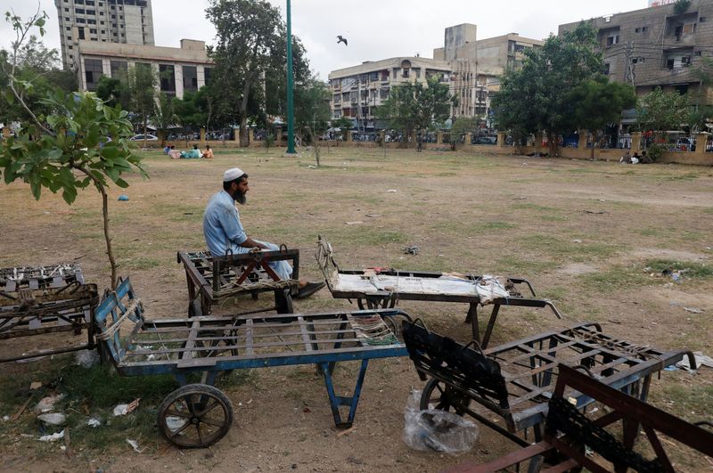 © Reuters. A labourer waits for work while sitting beside push trollies outside a market in Karachi, Pakistan June 8, 2023. REUTERS/Akhtar Soomro