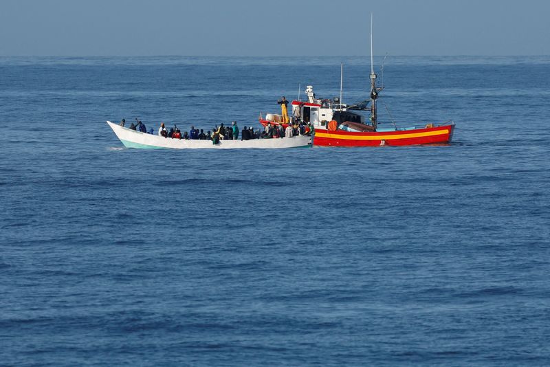 &copy; Reuters. قارب صيد يساعد مهاجرين على قارب خشبي بالقرب من ساحل جزر الكناري بأسبانيا في الثامن من يونيو حزيران 2023. تصوير: بورخا سواريز - رويترز.