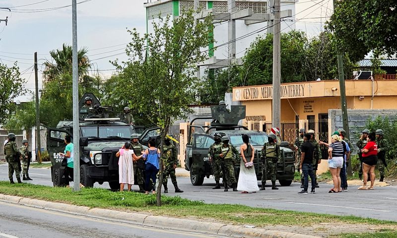 &copy; Reuters. مجموعة من الناس تقف بجانب جنود من الجيش المكسيكي يحرسون مسرح الجريمة التي قتل فيها جنود خمسة رجال عقب مطاردتهم في 18 مايو أيار 2023. تصوير : جاسي
