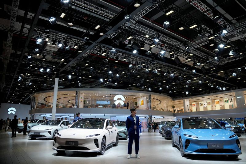 © Reuters. FILE PHOTO: A staff member stands near Nio ET5 cars at its booth at the Auto Shanghai show, in Shanghai, China, April 18, 2023. REUTERS/Aly Song/File Photo