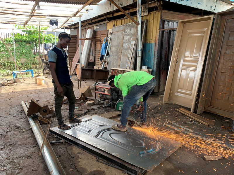 © Reuters. Shola Ojo, a Nigerian welder, works with his co-worker on a metal door in his workshop in Lagos, Nigeria, June 3, 2023. REUTERS/Seun Sanni