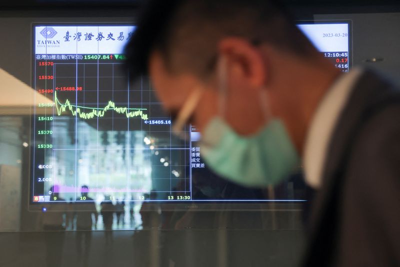 &copy; Reuters. FILE PHOTO: A man wearing a face mask passes in front of screens showing trading data while using an escalator outside Taiwan Stock Exchange in Taipei, Taiwan March 20, 2023. REUTERS/Annabelle Chih
