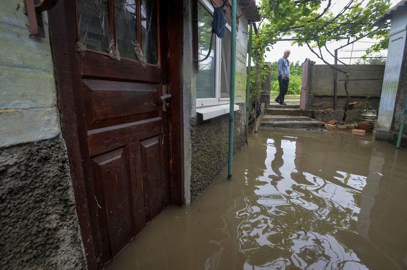 &copy; Reuters. أحد السكان المحليين ينظر إلي منزله الذي غمرته مياه الفيضانات يوم الاثنين عقب انهيار سد كاخوفكا في قرية بمنطقة خيرسون في أوكرانيا. تصوير: أول