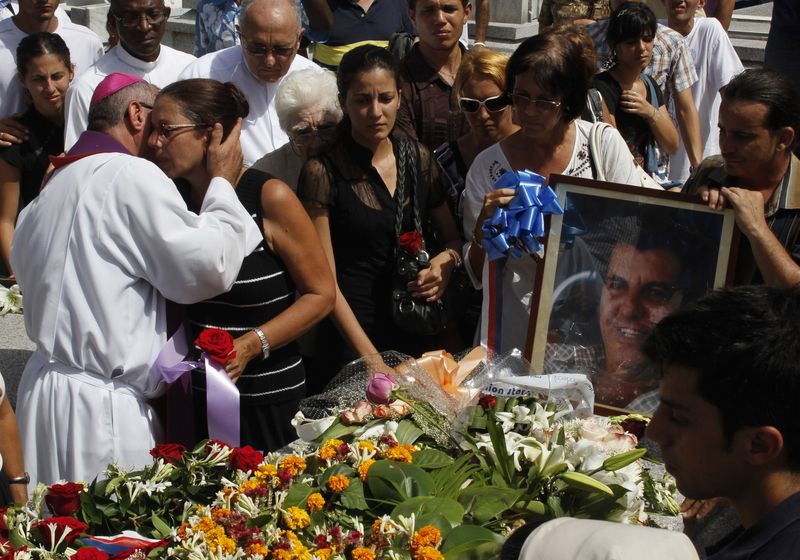 &copy; Reuters. Ofelia Acevedo, wife of Oswaldo Paya, one of Cuba's best-known dissidents, is comforted by a priest near the tomb of her husband after his burial in Havana July 24, 2012. Paya, leader of the Christian Liberation Movement, died on Sunday in a car crash, go