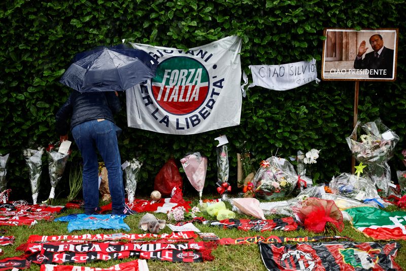 &copy; Reuters. Una persona lascia una lettera tra fiori e cimeli calcistici in memoria dell'ex premier Silvio Berlusconi, vicino a Villa San Martino ad Arcore, 13 giugno 2023. REUTERS/Yara Nardi