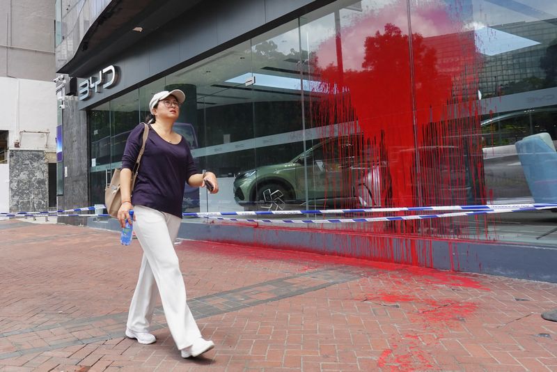 &copy; Reuters. FILE PHOTO: A woman walks past a splattered BYD store while police cordons are visible at the scene in Hong Kong, China June 12, 2023. REUTERS/Joyce Zhou/FILE PHOTO