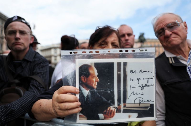 &copy; Reuters. A person holds a picture of former Italian Prime Minister Silvio Berlusconi on the day of his funeral, in Milan, Italy June 14, 2023. REUTERS/Yara Nardi
