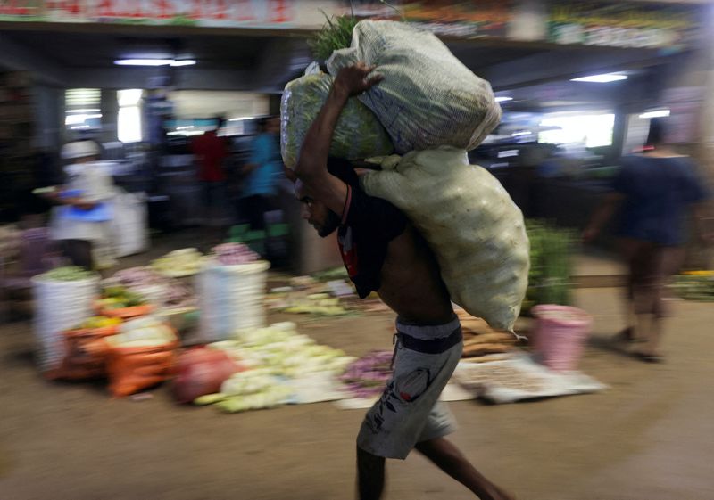 &copy; Reuters. FILE PHOTO: A worker carries sacks of vegetables at a wholesale market, as Sri Lanka's key inflation rate eases to 25.2% in May, in Colombo, Sri Lanka June 1, 2023. REUTERS/Dinuka Liyanawatte/File Photo